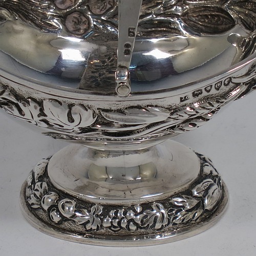 A very pretty Antique Victorian Sterling Silver sugar basket, having an oval shaped body, a swing-handle, and sitting on a pedestal foot, all hand-chased with floral and fruit decoration. Made by Jacobes J. Oasterbaan of London in 1878. The dimensions of this fine hand-made antique silver sugar basket are height 12.5 cms (5 inches), length 11.5 cms (4.5 inches), width 9 cms (3.5 inches), and it weighs approx. 192g (6.2 troy ounces).