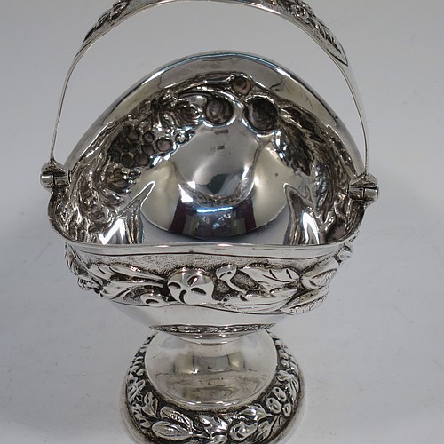 A very pretty Antique Victorian Sterling Silver sugar basket, having an oval shaped body, a swing-handle, and sitting on a pedestal foot, all hand-chased with floral and fruit decoration. Made by Jacobes J. Oasterbaan of London in 1878. The dimensions of this fine hand-made antique silver sugar basket are height 12.5 cms (5 inches), length 11.5 cms (4.5 inches), width 9 cms (3.5 inches), and it weighs approx. 192g (6.2 troy ounces).