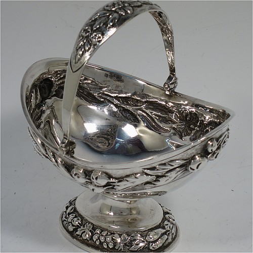A very pretty Antique Victorian Sterling Silver sugar basket, having an oval shaped body, a swing-handle, and sitting on a pedestal foot, all hand-chased with floral and fruit decoration. Made by Jacobes J. Oasterbaan of London in 1878. The dimensions of this fine hand-made antique silver sugar basket are height 12.5 cms (5 inches), length 11.5 cms (4.5 inches), width 9 cms (3.5 inches), and it weighs approx. 192g (6.2 troy ounces).