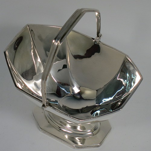 An Antique Edwardian Sterling Silver sugar basket in a Georgian style, having a plain octagonal panelled shaped body, with applied reeded borders, a reeded swing-handle, and sitting on a pedestal foot. Made by Thomas Bradbury and Sons of Sheffield in 1907. The dimensions of this fine hand-made antique silver sugar basket are height 14.5 cms (5.75 inches), length 12.5 cms (5 inches), width 10 cms (4 inches), and it weighs approx. 170g (5.5 troy ounces).    