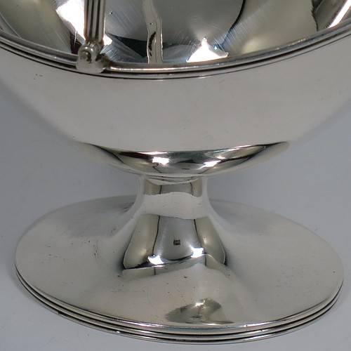An Antique Victorian Sterling Silver sugar basket in a Georgian style, having a plain oval shaped body, with applied reeded borders, a reeded swing-handle, and sitting on a pedestal foot. Made by Holland, Aldwinckle, and Slater of London in 1895. The dimensions of this fine hand-made antique silver sugar basket are height 14.5 cms (5.75 inches), length 13 cms (5 inches), width 9.5 cms (3.75 inches), and it weighs approx. 188g (6 troy ounces).