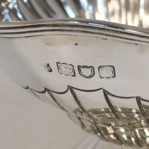 A very pretty Antique Victorian Sterling Silver sugar basket, having an oval body with tapering sides and hand-chased half-fluted decoration, with an applied reeded top border, a hinged and reeded swing-handle, and sitting on a plain oval stepped pedestal foot. This beautiful antique silver sweet-meat basket was made by Thomas Bradbury of London in 1897. The dimensions of this fine hand-made antique silver sugar basket are height (inc. handle) 13.5 cms (5.3 inches), length 13.5 cms (5.3 inches), width 9.5 cms (3.75 inches), and it weighs approx. 132g (4.3 troy ounces).