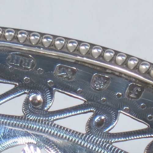 A very pretty Antique Georgian Sterling Silver sugar or sweetmeat basket, having an oval body, with hand-pierced neoclassical style decoration, an applied bead-edged border, a beeded swing-handle, and sitting on a matching pedestal foot. Made by Robert Hennell of London in 1781. The dimensions of this fine hand-made antique silver sweet-meat or sugar basket are height 13 cms (5 inches), length 15.5 cms (6 inches), width 12.5 cms (5 inches), and it weighs approx. 156g (5 troy ounces).
