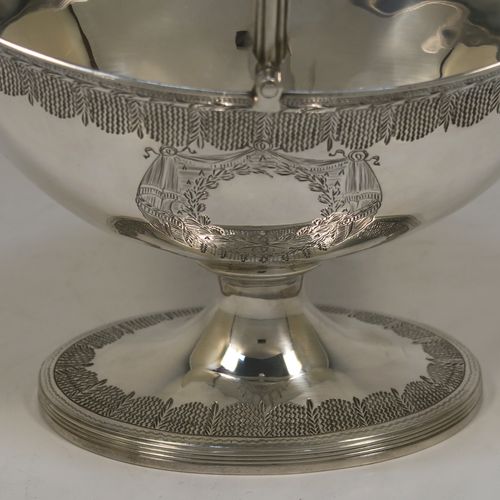 A very elegant and large Antique Georgian Sterling Silver sugar basket, having an oval body with tapering sides and hand-engraved neoclassical style decoration above two vacant cartouches on either side, with applied reeded borders, a hinged and reeded swing-handle, and sitting on a pedestal foot with matching decoration. This beautiful antique silver sweet-meat basket was made by Henry Chawner of London in 1795. The dimensions of this fine hand-made antique silver sugar basket are height (inc. handle) 18.5 cms (7.25 inches), length 16.5 cms (6.5 inches), and it weighs approx. 217g (7 troy ounces).