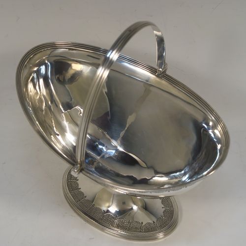 A very elegant and large Antique Georgian Sterling Silver sugar basket, having an oval body with tapering sides and hand-engraved neoclassical style decoration above two vacant cartouches on either side, with applied reeded borders, a hinged and reeded swing-handle, and sitting on a pedestal foot with matching decoration. This beautiful antique silver sweet-meat basket was made by Henry Chawner of London in 1795. The dimensions of this fine hand-made antique silver sugar basket are height (inc. handle) 18.5 cms (7.25 inches), length 16.5 cms (6.5 inches), and it weighs approx. 217g (7 troy ounces).