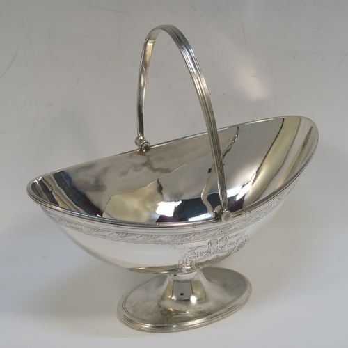 A very pretty Antique Victorian Sterling Silver sugar basket, having an oval body with tapering sides and hand-engraved bright-cut floral style decoration above two cartouches on either side, with applied reeded borders, a hinged and reeded swing-handle, and sitting on a plain oval pedestal foot. This beautiful antique silver sweet-meat basket was made by Joseph Braham of London in 1881. The dimensions of this fine hand-made antique silver sugar basket are height (inc. handle) 15 cms (6 inches), length 16 cms (6.3 inches), width 10 cms (4 inches), and it weighs approx. 178g (5.7 troy ounces). Please note that this item has a part-crest on one side.