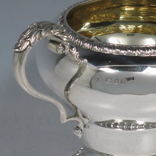 A Sterling Silver large sugar bowl, in a Georgian style, having a plain round baluster body, with an applied gadroon border, two scroll side-handles with Anthemion leaf thumb-pieces, a gold-gilt interior, and all sitting on a pedestal foot with hand-chased fluted decoration. Made by Charles Townley & John Thomas of London in 1928. The dimensions of this fine hand-made silver sugar bowl are height 13.5 cms (5.25 inches), spread across handles 19 cms (7.5 inches), and it weighs approx. 448g (14.5 troy ounces).   