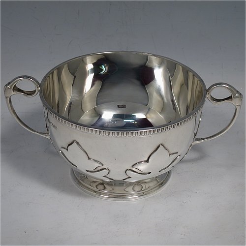 An Antique Sterling Silver sugar bowl, in a Georgian style, having a round bellied body, with unusual applied cut-card work and a gadroon border, two scroll side-handles, and all sitting on a pedestal foot. Made by Alexander Clarke & Co., of Birmingham 1913. The dimensions of this fine hand-made silver sugar bowl are height 7 cms (2.75 inches), spread across handles 15 cms (6 inches), and it weighs approx. 233g (7.5 troy ounces).    