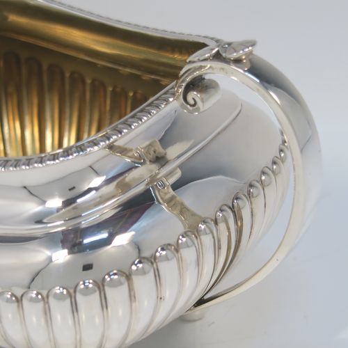 A very handsome Antique Victorian large Sterling Silver sugar bowl, having a rounded rectangular and bellied body, with hand-chased half-fluted decoration, two scroll side-handles, an applied gadroon top border, a gold-gilt interior, and all sitting on four ball feet. This elegant silver sugar bowl was made by James Dixon and Sons of Sheffield in 1885. The dimensions of this fine hand-made antique silver sugar bowl are length (inc. handles) 19 cms (7.5 inches), height 11 cms (4.25 inches), width 11.5 cms (4.5 inches), and it weighs approx. 410g (12 troy ounces).   