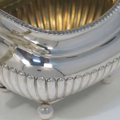 A very handsome Antique Victorian large Sterling Silver sugar bowl, having a rounded rectangular and bellied body, with hand-chased half-fluted decoration, two scroll side-handles, an applied gadroon top border, a gold-gilt interior, and all sitting on four ball feet. This elegant silver sugar bowl was made by James Dixon and Sons of Sheffield in 1885. The dimensions of this fine hand-made antique silver sugar bowl are length (inc. handles) 19 cms (7.5 inches), height 11 cms (4.25 inches), width 11.5 cms (4.5 inches), and it weighs approx. 410g (12 troy ounces).   