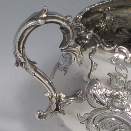 Antique Victorian sterling silver sugar bowl, having a round bellied hand-chased body with floral decoration, scroll handles, and sitting on scroll feet. Made by Martin Hall & Co., of Sheffield in 1856. The dimensions of this fine hand-made silver sugar bowl are height 13.5 cms (5.25 inches), width 22 cms (8.6 inches), and it weighs approx. 436g (14 troy ounces).