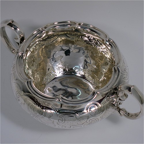 An Antique late Georgian (William IV) Sterling Silver sugar bowl, having a round bellied body with hand-chased floral decoration, an applied lobed top border, with two scroll side handles, and sitting on a collet foot. Made by the Barnard Brothers of London in 1837. The dimensions of this fine hand-made antique silver sugar bowl are height 10 cms (4 inches), width across handles 21.5 cms (8.5 inches), and it weighs approx. 374g (12 troy ounces).