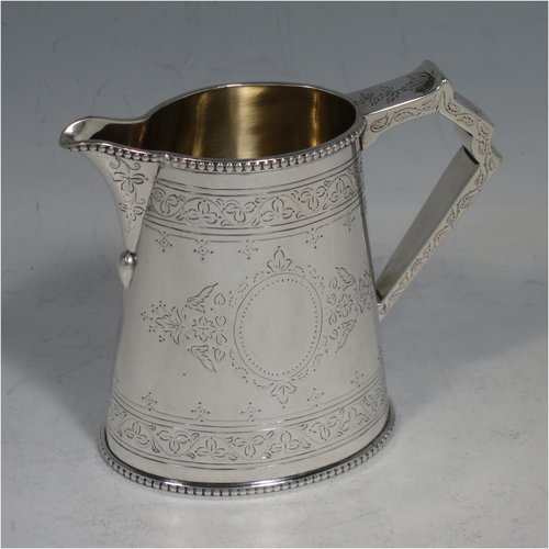 An Antique Victorian Sterling silver sugar and creamer set, having oval bodies with hand-engraved floral decoration, applied beaded borders, gold-gilt interiors, and angular handles. Made by Goldsmiths & Silversmiths of London in 1881. The dimensions of this fine hand-made antique silver cream and sugar set are height of creamer 9 cms (3.5 inches), length of sugar bowl 16 cms (6.25 inches), and with a total weight approx. 303g (9.8 troy ounces).