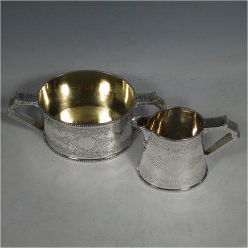 An Antique Victorian Sterling silver sugar and creamer set, having oval bodies with hand-engraved floral decoration, applied beaded borders, gold-gilt interiors, and angular handles. Made by Goldsmiths & Silversmiths of London in 1881. The dimensions of this fine hand-made antique silver cream and sugar set are height of creamer 9 cms (3.5 inches), length of sugar bowl 16 cms (6.25 inches), and with a total weight approx. 303g (9.8 troy ounces).