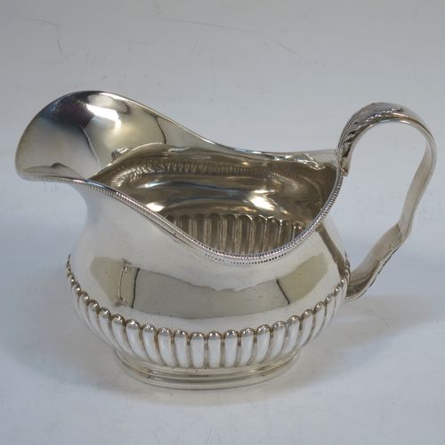 A pretty Antique Victorian Sterling Silver sugar bowl and cream jug set, having oval bellied bodies with hand-chased half-fluted decoration, applied rope-twist borders, scroll side-handles with anthemion leaf thumb-pieces, and all sitting on collet feet. Made by Frederick Bradford Macrea of London in 1887. The dimensions of this fine hand-made antique silver sugar and creamer set are length of sugar bowl (inc. handles) 16.5 cms (6.5 inches), height 9 cms (3.5 inches), width 9.5 cms (3.75 inches), and with a total weight of approx. 310g (10 troy ounces).