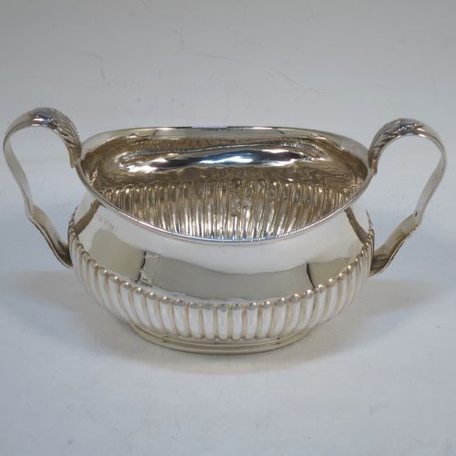 A pretty Antique Victorian Sterling Silver sugar bowl and cream jug set, having oval bellied bodies with hand-chased half-fluted decoration, applied rope-twist borders, scroll side-handles with anthemion leaf thumb-pieces, and all sitting on collet feet. Made by Frederick Bradford Macrea of London in 1887. The dimensions of this fine hand-made antique silver sugar and creamer set are length of sugar bowl (inc. handles) 16.5 cms (6.5 inches), height 9 cms (3.5 inches), width 9.5 cms (3.75 inches), and with a total weight of approx. 310g (10 troy ounces).