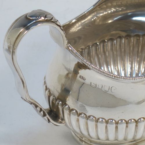 A pretty Antique Victorian Sterling Silver sugar bowl and cream jug set, having oval bellied bodies with hand-chased half-fluted decoration, applied rope-twist borders, scroll side-handles with anthemion leaf thumb-pieces, and all sitting on collet feet. Made by Frederick Bradford Macrea of London in 1887. The dimensions of this fine hand-made antique silver sugar and creamer set are length of sugar bowl (inc. handles) 16.5 cms (6.5 inches), height 9 cms (3.5 inches), width 9.5 cms (3.75 inches), and with a total weight of approx. 310g (10 troy ounces).