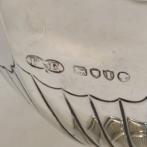 A very pretty Antique Victorian Sterling Silver sugar basket and cream jug set, having Neoclassical style panelled bodies with hand-chased half-fluted decoration, with applied reeded borders, the sugar basket with a swing-handle, and all sitting on pedestal feet. This elegant antique silver cream and sugar set was made by Frederick Elkington of London in 1884. The dimensions of this fine hand-made antique silver sugar and creamer set are height of cream jug 12.5 cms (5 inches), length of sugar basket 12 cms (4.75 inches), with a total weight of approx. 252g (8.1 troy ounces).