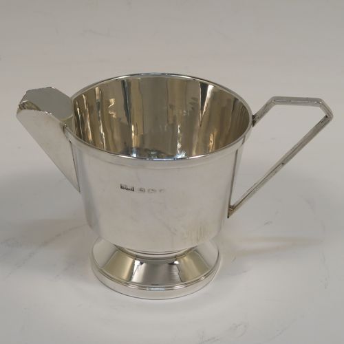 An elegant Sterling Silver pair of Art Deco sugar bowl and creamer set, having plain round bodies with tapering sides and reeded hand-chased decoration, with geometrical side-handles, and all sitting on round pedestal feet. This handsome silver sugar and cream set was made by A. L. Davenport of Birmingham in 1931. The dimensions of this fine hand-made silver sugar bowl and cream jug set are height of cream jug 8 cms (3 inches), width of sugar bowl 15 cms (6 inches), and the total weight is approx. 215g (7 troy ounces).