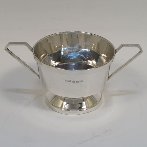 An elegant Sterling Silver pair of Art Deco sugar bowl and creamer set, having plain round bodies with tapering sides and reeded hand-chased decoration, with geometrical side-handles, and all sitting on round pedestal feet. This handsome silver sugar and cream set was made by A. L. Davenport of Birmingham in 1931. The dimensions of this fine hand-made silver sugar bowl and cream jug set are height of cream jug 8 cms (3 inches), width of sugar bowl 15 cms (6 inches), and the total weight is approx. 215g (7 troy ounces).
