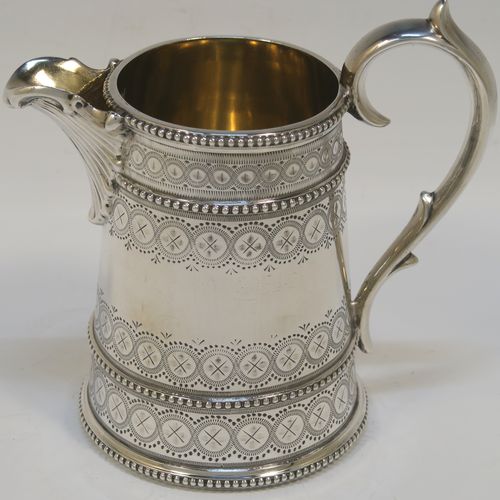 A large, beautiful and heavy Antique Victorian Sterling Silver sugar and creamer set, having round bodies with tapering sides and hand-engraved bright-cut floral decoration, with applied beaded borders, gold-gilt interiors, cast scroll side-handles, and all sitting on flat bases. This very pretty sugar and cream set was made by the Bradbury Brothers of London in 1869. The dimensions of this fine hand-made antique silver cream and sugar set are height of creamer 11.5 cms (4.5 inches), diameter of sugar bowl 10 cms (4 inches), and with a total weight approx. 639g (21 troy ounces).
