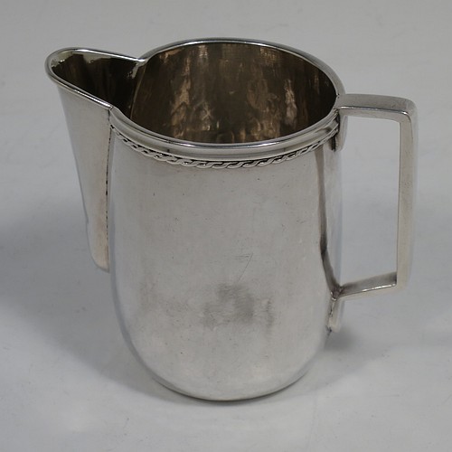 A very attractive Arts and Crafts Sterling Silver sugar and creamer set, having round bodies with hand-hammered plenished decoration, with applied reeded and rope-twist top borders, all sitting on flat bases. Made by Edward Spencer of the Artificiers Guild of London in 1928. The dimensions of this fine hand-made Arts and Crafts silver sugar and creamer set are diameter of sugar bowl 9 cms (3.5 inches), height of cream jug 7 cms (2.75 inches), with a total weight of 173g (5.6 troy ounces).