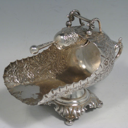 Antique Victorian sterling silver sugar scuttle, having a hand-chased body with floral decoration, two cast twin-scroll handles, an original scoop with gold-gilt interior, and sitting on a pedestal foot with four cushion feet. Made by Walker and Hall of Birmingham in 1899. Length 16 cms (6.25 inches), height 12.5 cms (5 inches), width 8 cms (3 inches). Weight approx. 216g (7 troy ounces).