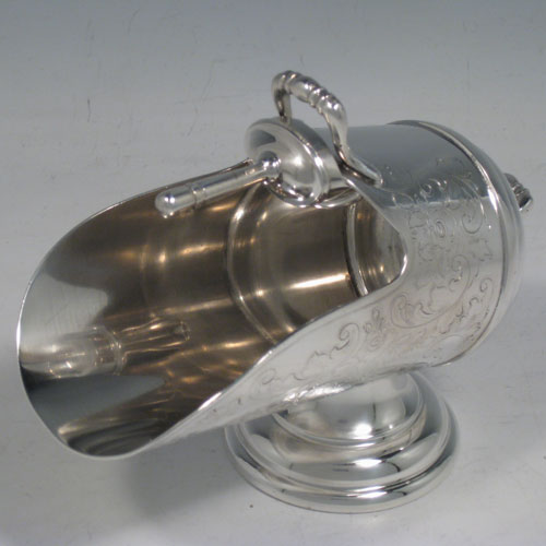 Antique Victorian silver-plated sugar scuttle, having a hand-engraved body with floral decoration, two cast scroll handles, an original scoop, and sitting on a pedestal foot. Made in ca. 1890. The dimensions of this fine hand-made silver-plated sugar scuttle are length 15 cms (6 inches), height 11.5 cms (4.5 inches), and width 7.5 cms (3 inches).