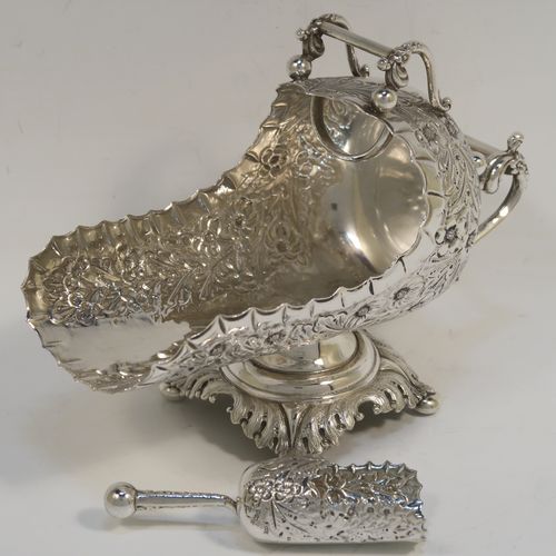 A rare and very pretty Antique Victorian Sterling Silver sugar scuttle, having a hand-chased body with floral decoration, two cast twin-scroll handles, an original scoop, and sitting on a pedestal foot with four cushion feet. This beautiful antique silver sugar scuttle was made by William Davenport of Birmingham in 1900. The dimensions of this fine hand-made silver sugar scuttle are length 15 cms (6 inches), height 12 cms (4.75 inches), width 8 cms (3 inches), and it weighs approx. 209g (6.7 troy ounces).