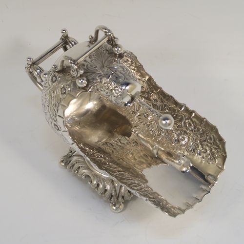 A rare and very pretty Antique Victorian Sterling Silver sugar scuttle, having a hand-chased body with floral decoration, two cast twin-scroll handles, an original scoop, and sitting on a pedestal foot with four cushion feet. This beautiful antique silver sugar scuttle was made by William Davenport of Birmingham in 1900. The dimensions of this fine hand-made silver sugar scuttle are length 15 cms (6 inches), height 12 cms (4.75 inches), width 8 cms (3 inches), and it weighs approx. 209g (6.7 troy ounces).