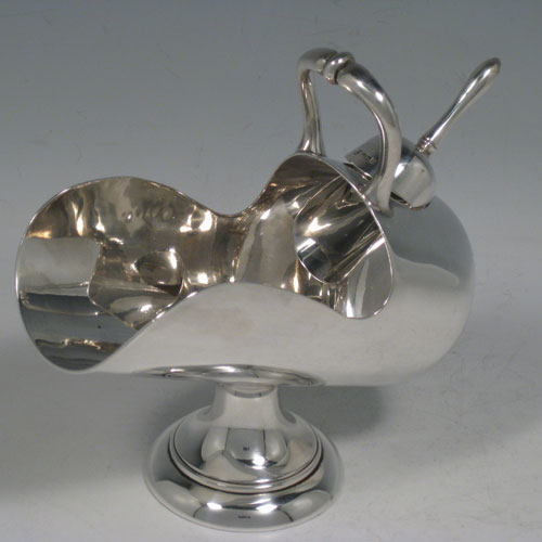 Antique Edwardian sterling silver sugar scuttle, having a plain body, a cast scroll handle, an original scoop, and sitting on a pedestal foot. Made by the Deakin Brothers of Sheffield in 1909. The dimensions of this fine hand-made silver sugar scuttle are length 16 cms (6.25 inches), height 14 cms (5.5 inches), width 7 cms (2.75 inches), and it weighs approx. 256g (8 troy ounces).