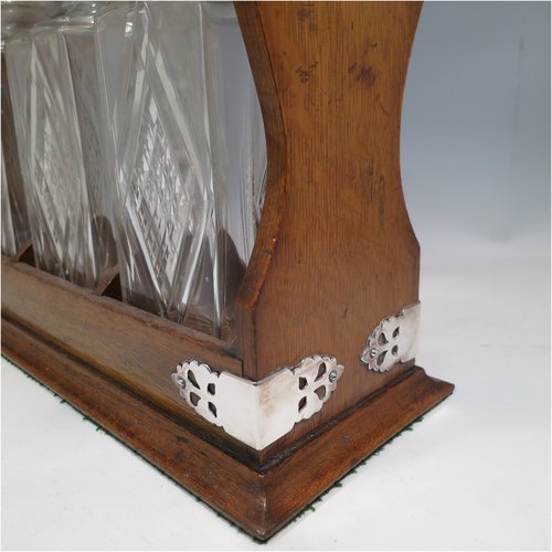 An Antique Edwardian silver plated and wood-framed three bottle tantalus, with hand-cut crystal decanters and stoppers, all mounted in an oak frame with silver-plated swing handle, a patented lock mechanism, and hand-cut silver-plated mounts. Made in ca. 1905. The dimensions of this fine hand-made antique silver-plated and wooden framed tantalus are height 34 cms (13.5 inches), length , width 37 cms (14.5 inches), and width 14 cms (5.5 inches). Please note that shipping and insurance would be extra for this item so please check with us first before ordering.