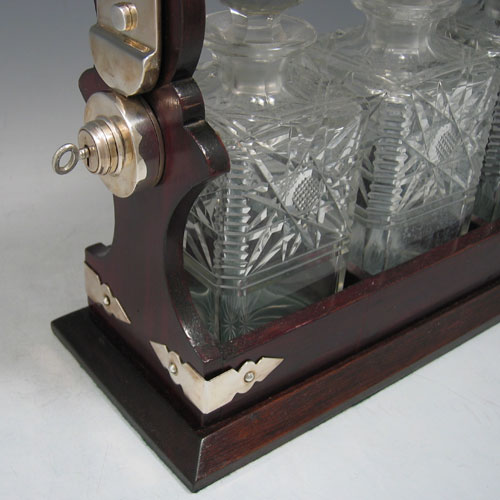 Antique Edwardian silver plated and wood-framed three bottle tantalus with hand-cut crystal decanters made in ca. 1910. Height 30 cms, width 35 cms.