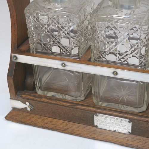 A very handsome Antique Silver-plated and wood framed three-bottle tantalus, with original hand-cut crystal decanters and stoppers, all in an oak (poss.) wooden frame with silver-plated and nickel pinned mounts, with a patented lock mechanism and key. The presentation inscription is engraved onto a sterling silver plaque with hallmarks, which indicate that this beautiful antique silver-plated and wood tantalus was made by Walker and Hall of Birmingham in 1912. The dimensions of this fine hand-made antique three-bottle tantalus are length 36 cms (14 inches), height 32 cms (12.5 inches), and depth 14 cms (5.5 inches).