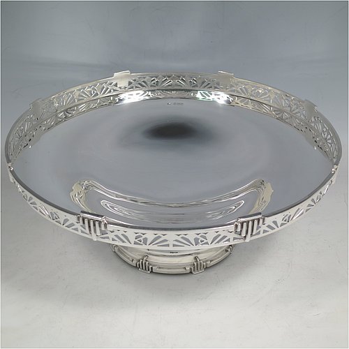 A Sterling Silver Art Deco tazza dish, having a round plain body, with a hand-pierced gallery border and applied Art Deco motifs, and all sitting on a matching pedestal foot. Made by Walker & Hall of Sheffield in 1933. The dimensions of this fine hand-made silver Art Deco tazza dish are height 10 cms (4 inches), diameter 25.5 cms (10 inches), and it weighs approx. 530g (17 troy ounces).   