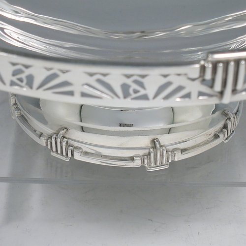 A Sterling Silver Art Deco tazza dish, having a round plain body, with a hand-pierced gallery border and applied Art Deco motifs, and all sitting on a matching pedestal foot. Made by Walker & Hall of Sheffield in 1933. The dimensions of this fine hand-made silver Art Deco tazza dish are height 10 cms (4 inches), diameter 25.5 cms (10 inches), and it weighs approx. 530g (17 troy ounces).
