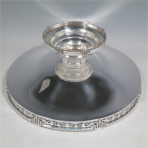 A Sterling Silver Art Deco tazza dish, having a round plain body, with a hand-pierced gallery border and applied Art Deco motifs, and all sitting on a matching pedestal foot. Made by Walker & Hall of Sheffield in 1933. The dimensions of this fine hand-made silver Art Deco tazza dish are height 10 cms (4 inches), diameter 25.5 cms (10 inches), and it weighs approx. 530g (17 troy ounces).