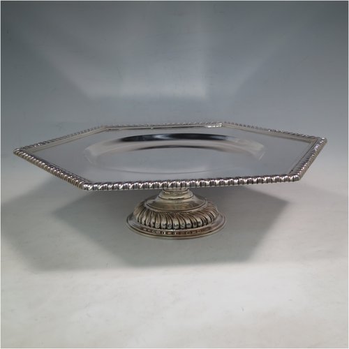An Antique Sterling Silver very heavy tazza cake dish, having a plain hexagonal body, with a gadroon border, and sitting on a pedestal foot with applied cut-card work and hand-chased fluting. Made by Sebastian Garrard of London in 1911. The dimensions of this fine hand-made antique silver tazza dish are height 8 cms (3 inches), width of plate 31 cms (12.25 inches), and the weight is approx. 1,425g (46 troy ounces).