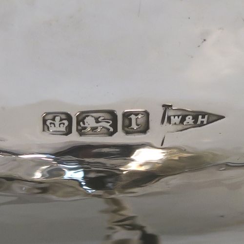 A very handsome Antique Edwardian Sterling Silver Arts and Crafts style tazza dish, having a round bowl attached to a pedestal foot with three scroll arms, and an all-over hand-hammered or plenished finish. This beautiful silver tazza dish was made by Walker and Hall of Sheffield in 1909. The dimensions of this fine hand-made antique silver dish are height 9 cms (3.5 inches), diameter 16 cms (6.3 inches), and it weighs approx. 203g (6.5 troy ounces).   
