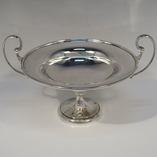 A very handsome Antique Sterling Silver tazza dish, having a plain round body with an applied reeded border, with two scroll side-handles, and all sitting on a matching pedestal foot. This elegant silver tazza bowl was made by Holland, Aldwinckle and Slater of Birmingham in 1914. The dimensions of this fine hand-made antique silver tazza dish are height 15 cms (6 inches), diameter 19 cms (7.5 inches), and it weighs approx. 550g (17.7 troy ounces).   