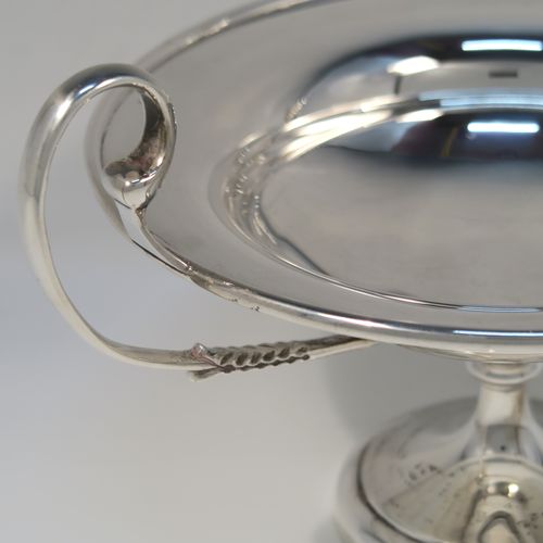 A very handsome Antique Sterling Silver tazza dish, having a plain round body with an applied reeded border, with two scroll side-handles, and all sitting on a matching pedestal foot. This elegant silver tazza bowl was made by Holland, Aldwinckle and Slater of Birmingham in 1914. The dimensions of this fine hand-made antique silver tazza dish are height 15 cms (6 inches), diameter 19 cms (7.5 inches), and it weighs approx. 550g (17.7 troy ounces).