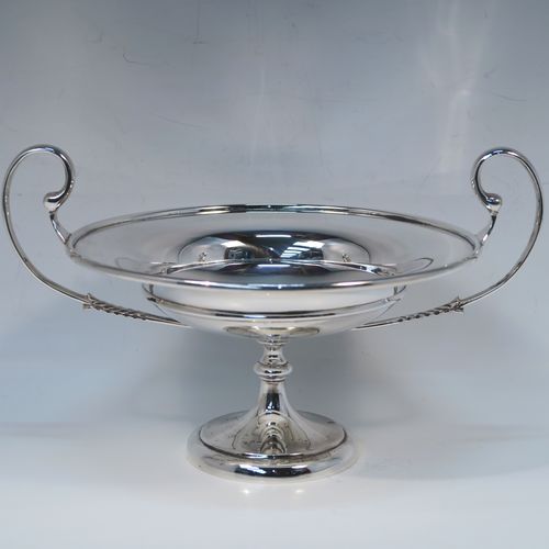 A very handsome Antique Sterling Silver tazza dish, having a plain round body with an applied reeded border, with two scroll side-handles, and all sitting on a matching pedestal foot. This elegant silver tazza bowl was made by Holland, Aldwinckle and Slater of Birmingham in 1914. The dimensions of this fine hand-made antique silver tazza dish are height 15 cms (6 inches), diameter 19 cms (7.5 inches), and it weighs approx. 550g (17.7 troy ounces).