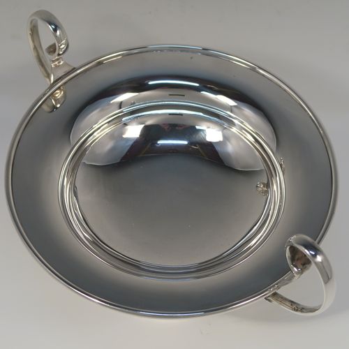 A very handsome Antique Sterling Silver tazza dish, having a plain round body with an applied reeded border, with two scroll side-handles, and all sitting on a matching pedestal foot. This elegant silver tazza bowl was made by Holland, Aldwinckle and Slater of Birmingham in 1914. The dimensions of this fine hand-made antique silver tazza dish are height 15 cms (6 inches), diameter 19 cms (7.5 inches), and it weighs approx. 550g (17.7 troy ounces).