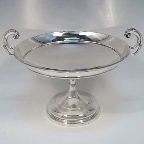 A very handsome Antique Sterling Silver Tazza dish, having a plain round body, with applied reeded borders and two scroll side handles, all raised above and sitting on a plain round pedestal foot. This elegant silver dish was made by Walker and Hall of Sheffield in 1912. The dimensions of this fine hand-made antique silver Tazza dish are height 16.5 cms (6.5 inches), diameter 20 cms (8 inches), and it weighs approx. 464g (15 troy ounces).  