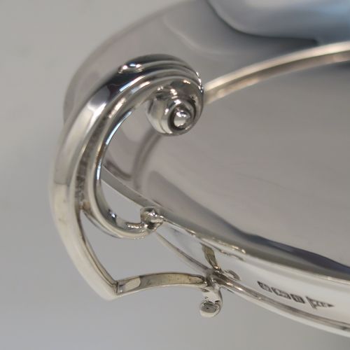 A very handsome Antique Sterling Silver Tazza dish, having a plain round body, with applied reeded borders and two scroll side handles, all raised above and sitting on a plain round pedestal foot. This elegant silver dish was made by Walker and Hall of Sheffield in 1912. The dimensions of this fine hand-made antique silver Tazza dish are height 16.5 cms (6.5 inches), diameter 20 cms (8 inches), and it weighs approx. 464g (15 troy ounces).
