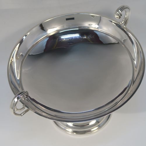 A very handsome Antique Sterling Silver Tazza dish, having a plain round body, with applied reeded borders and two scroll side handles, all raised above and sitting on a plain round pedestal foot. This elegant silver dish was made by Walker and Hall of Sheffield in 1912. The dimensions of this fine hand-made antique silver Tazza dish are height 16.5 cms (6.5 inches), diameter 20 cms (8 inches), and it weighs approx. 464g (15 troy ounces).
