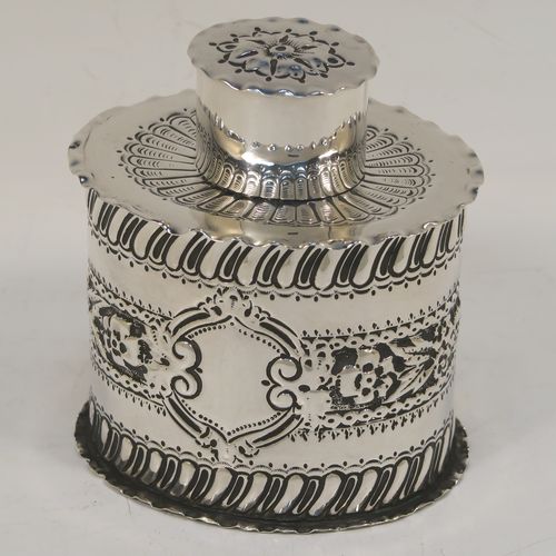 A very pretty Antique Victorian Sterling Silver tea caddy box, having an oval straight-sided body with hand-chased floral, scroll, and swirl-fluted decoration, with a vacant cartouche on both sides and with hand-crimped borders, a pull-off lid with matching decoration, and all sitting on a flat base. This beautiful antique silver tea caddy box was made by Jackson and Fullerton of London in 1899. The dimensions of this fine hand-made antique silver tea caddy box are height 9 cms (3.5 inches), length 8 cms (3.25 inches), width 6.5 cms (2.5 inches), and it weighs approx. 113g (3.6 troy ounces).