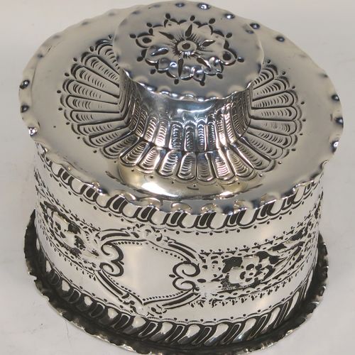 A very pretty Antique Victorian Sterling Silver tea caddy box, having an oval straight-sided body with hand-chased floral, scroll, and swirl-fluted decoration, with a vacant cartouche on both sides and with hand-crimped borders, a pull-off lid with matching decoration, and all sitting on a flat base. This beautiful antique silver tea caddy box was made by Jackson and Fullerton of London in 1899. The dimensions of this fine hand-made antique silver tea caddy box are height 9 cms (3.5 inches), length 8 cms (3.25 inches), width 6.5 cms (2.5 inches), and it weighs approx. 113g (3.6 troy ounces).