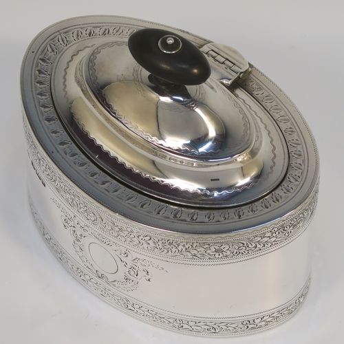 A very pretty Antique Edwardian Sterling Silver tea caddy box, having an oval straight-sided body, a wooden finial sitting on an oval domed and hinged lid, all with hand-engraved bands of floral decoration, together with floral engraving surrounding oval vacant cartouches on either side, and all sitting on a flat base. This beautiful antique silver tea caddy box was made by William Hutton and Sons of Sheffield in 1902. The dimensions of this fine hand-made antique silver tea caddy box are height 9.5 cms (3.75 inches), length 11 cms (4.25 inches), depth 7.5 cms (3 inches), and it weighs approx. 230g (7.4 troy ounces).   
