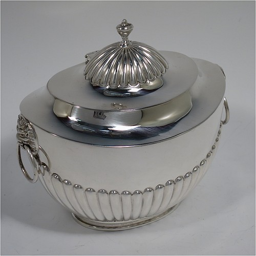 An Antique Edwardian Sterling Silver tea caddy box, having an oval bellied body with hand-chased half-fluted decoration, two lion-mask and ring side-handles, a hinged domed lid with matching fluting and a cast urn finial, and all sitting on a collet foot. Made by Goldsmiths and Silversmiths of London in 1906. The dimensions of this fine hand-made antique silver tea caddy box are height 11 cms (4.25 inches), length 12.5 cms (5 inches), width 8 cms (3.25 inches), and it weighs approx. 198g (6.4 troy ounces).   